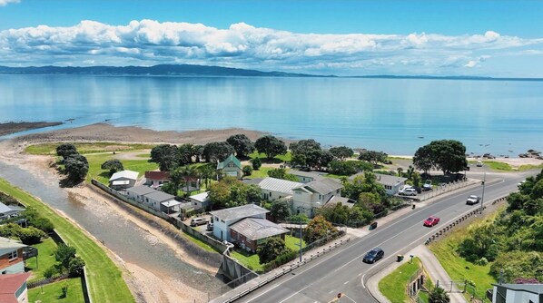 An aerial view of a coastal town with houses, a road, and a body of water.