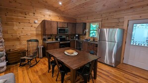 A wooden-paneled kitchen with a dining table, chairs, a refrigerator, and a microwave. - Incredible secluded cabin featuring amazing forest views off of the back deck! (Laurelville)