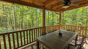 A wooden deck with a table and chairs, overlooking a forest. - Incredible secluded cabin featuring amazing forest views off of the back deck! (Laurelville)