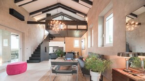 A spacious living area with a staircase, a dining area, and a kitchen in the background.