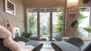 A modern room with two grey chairs, a small table, and a view of greenery outside.