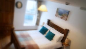 Een bed met een houten hoofdeinde, een raam met uitzicht en een lamp op een nachtkastje.