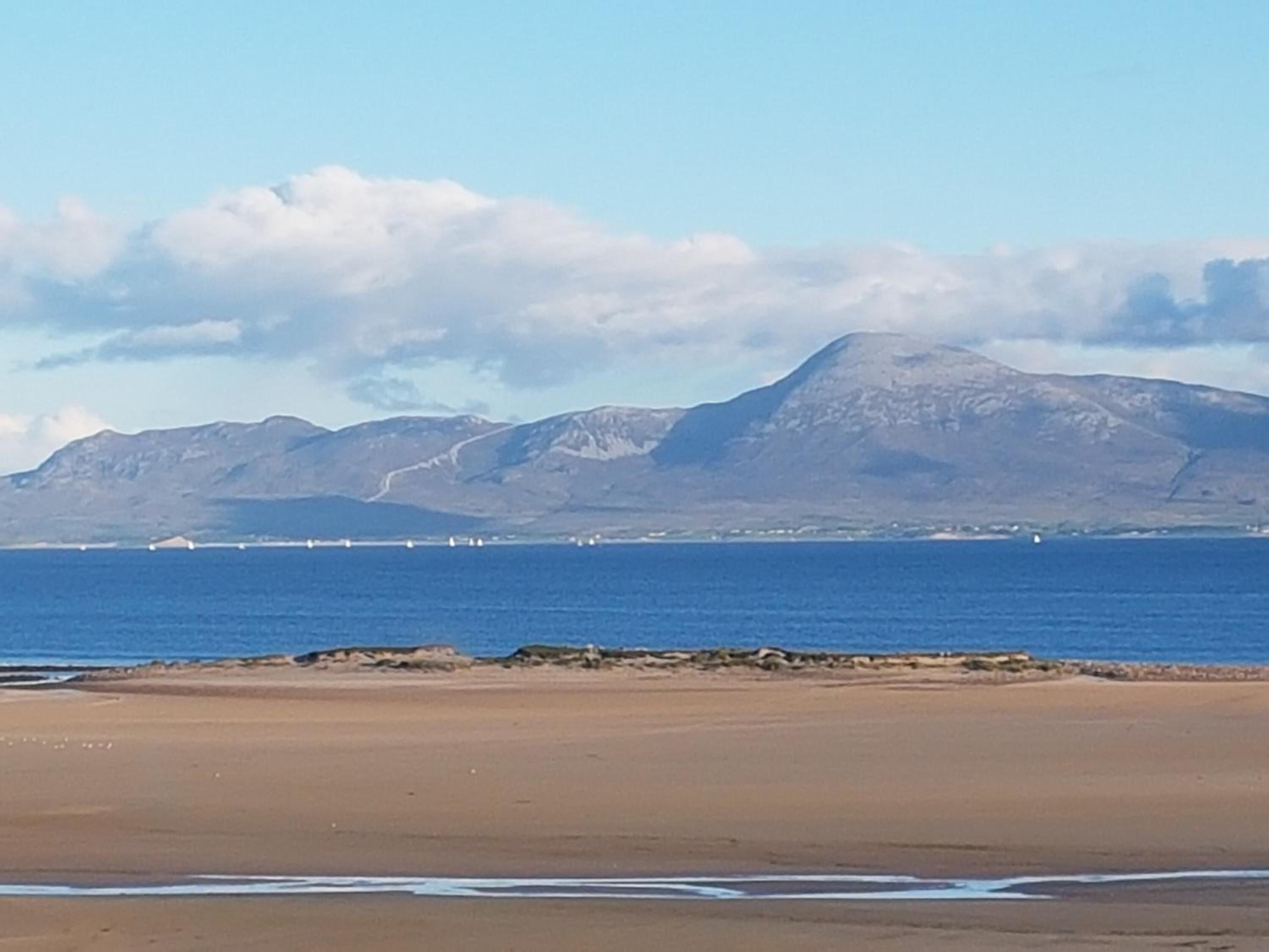 Una playa con una montaña al fondo y un cielo despejado.