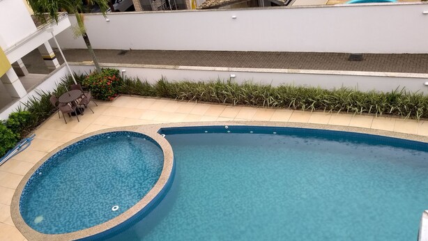 A swimming pool with a hot tub, surrounded by a tiled patio and greenery. - BEAUTIFUL AND COMFORTABLE 3QTS APARTMENT ON THE BEACH OF ENGLISH IN 180 MTS FROM THE BEACH (Ingleses do Rio Vermelho)