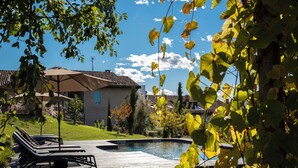 A swimming pool with lounge chairs, a wooden deck, and a house with a tiled roof. - ROSTAGNI 1834: BEAUTIFUL APT IN VILLA WITH POOL NEAR BAROLO (Novello)