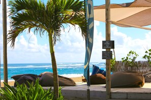 A beachside lounge with a view of the ocean, palm trees, and a sign indicating no smoking. - KiteBeach Agualina Oceanfront Condo Complex in Hotel (Cabarete)
