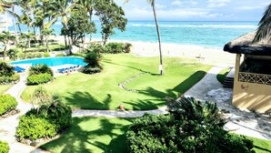 A resort with a swimming pool, well-maintained lawn, palm trees, and a view of the ocean. - KiteBeach Agualina Oceanfront Condo Complex in Hotel (Cabarete)