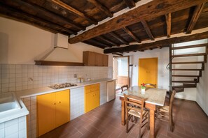 A kitchen with yellow cabinets, a white countertop, and a wooden ceiling.