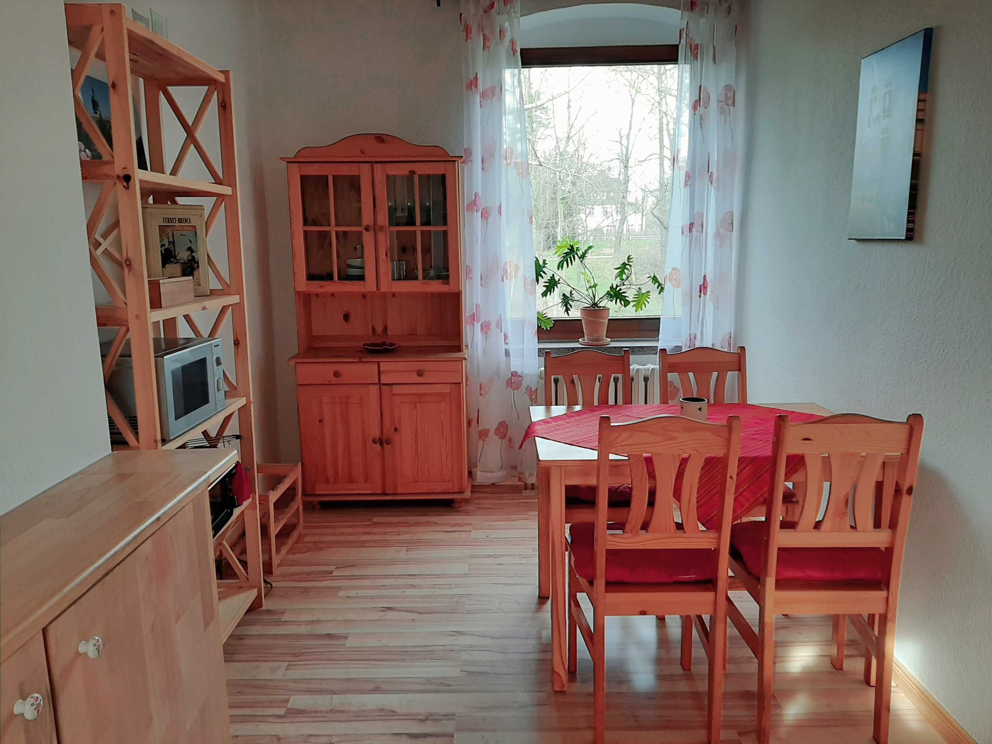 Una cocina compacta con armarios de madera, un microondas y una zona de comedor con mesa y sillas.