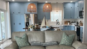 Eine moderne Küche mit blauen Schränken, einem Edelstahl-Kühlschrank und einem Essbereich mit braunem Ledersofa und Zierkissen.