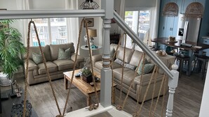 Ein geräumiger Wohnbereich mit hoher Decke, Deckenventilator und Treppe mit einer Taustraube.