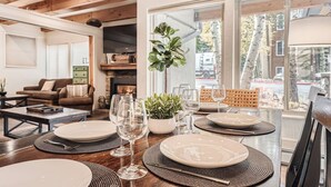 Un'area pranzo con un tavolo di legno apparecchiato per quattro, circondata da un accogliente soggiorno con camino e posti a sedere confortevoli.