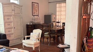 A cozy living room with a wooden cabinet, a dining table with chairs, a small side table, and a colorful woven basket. - Villa Coyoacan (Mexico City)