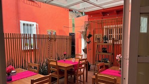 An outdoor dining area with wooden tables and chairs, a wooden fence, and potted plants. - Villa Coyoacan (Mexico City)