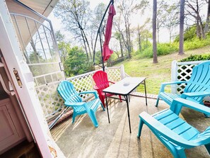 A patio with blue chairs and a table, a red chair, and a white lattice fence. - [Quite Oasis~4]5bds]1.5BT]3BR@Stockbridge GA (Stockbridge)