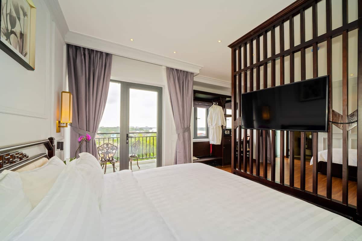 A hotel room with a large bed, a TV, a balcony with a view, and a wardrobe.