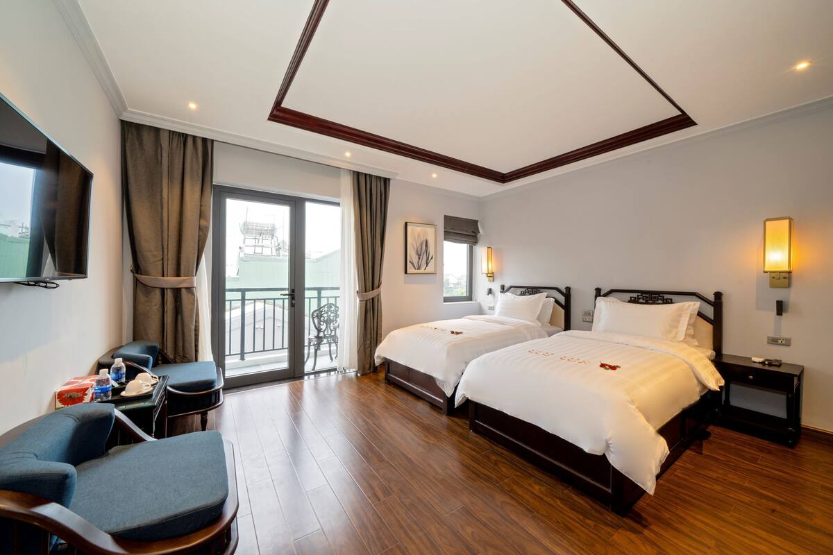 A hotel room with two beds, a TV, a desk, and a chair.