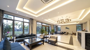 A spacious living area with a sofa set, a coffee table, and a dining area with chairs. -  Eco Lux Riverside Hotel & Spa (Da Nang)