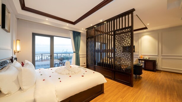 A spacious bedroom with a large bed, a view of the outdoors, and a partition with intricate patterns. -  Eco Lux Riverside Hotel & Spa (Da Nang)