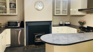Una cucina con microonde, fornelli, forno e un orologio appeso al muro.