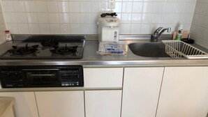 Una cocina compacta equipada con estufa a gas, cafetera, lavavajillas y pileta.
