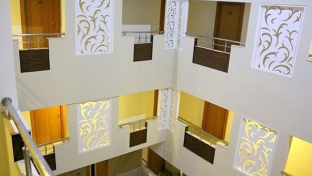 Un interno a più livelli con una scala centrale, pannelli decorativi e una porta in legno.