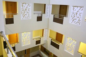A multi-level interior with a central staircase, decorative panels, and a wooden door. - Hotel Apple Park (Coimbatore)