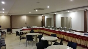 Una sala conferenze con un lungo tavolo, diverse sedie e un'area buffet.