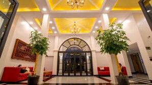 A hotel lobby with a high ceiling, chandeliers, red sofas, and potted plants. - Angkor Zhe Jiang Hotel (Siem Reap)