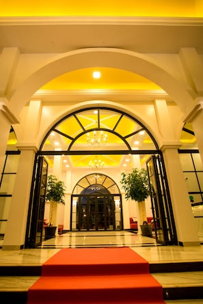 Enter through a grand symmetrical archway into a beautifully appointed lobby with a marble floor and elegant chandelier.