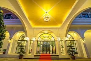 Stunning grand entrance with a central doorway, flanked by double doors and ornate chandeliers.