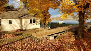 Une maison avec un petit porche et une jetée qui s’avance dans un lac.
