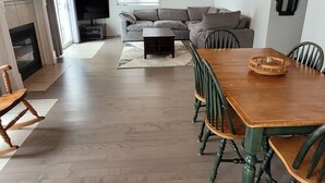 Un vaste espace de vie doté d’un plafond en bois, d’une cheminée, d’un canapé et d’une table à manger avec des chaises.