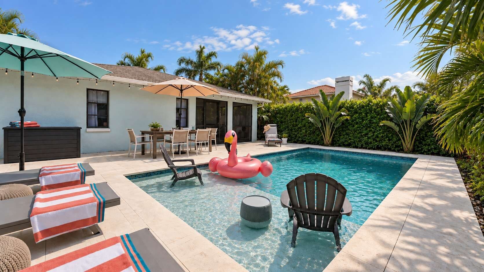 A swimming pool with lounge chairs, a flamingo float, and a dining area with chairs and a table.