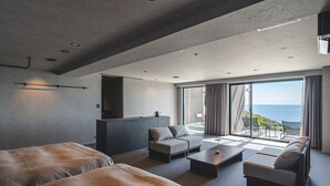 A modern hotel room with a large bed, a sofa, a coffee table, and a balcony with a view of the sea. - TheMana Village (Tosashimizu)