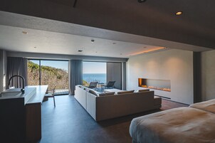 Una habitación de hotel moderna con una cama grande, un sofá, un comedor y una chimenea.