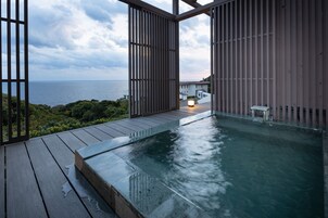 Una terraza de madera con piscina, con vistas a un cuerpo de agua y vegetación.