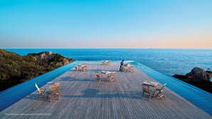 An infinity pool with wooden deck and lounge chairs overlooking the ocean. - TheMana Village (Tosashimizu)