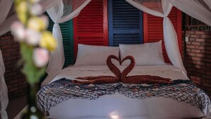 Een bed met hemelbed, een handdoekarrangement in de vorm van een hart en een musketinendeken.
