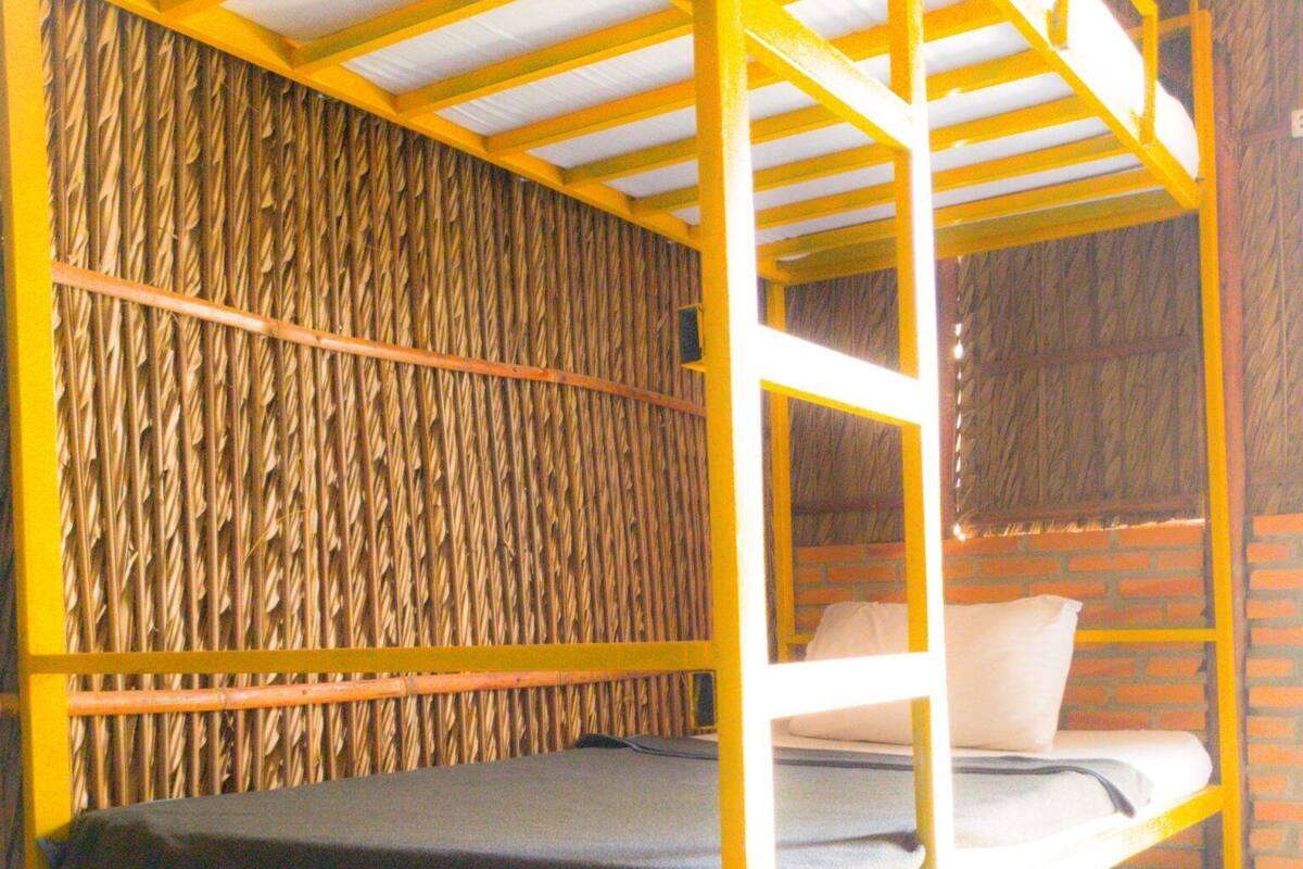 A bunk bed with a woven wall behind it.