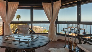 A balcony with a table, chairs, and a wine cart.