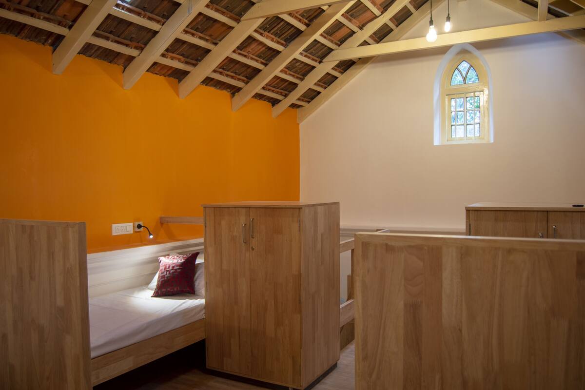A room with a wooden bunk bed, a small window, and a wooden wardrobe.