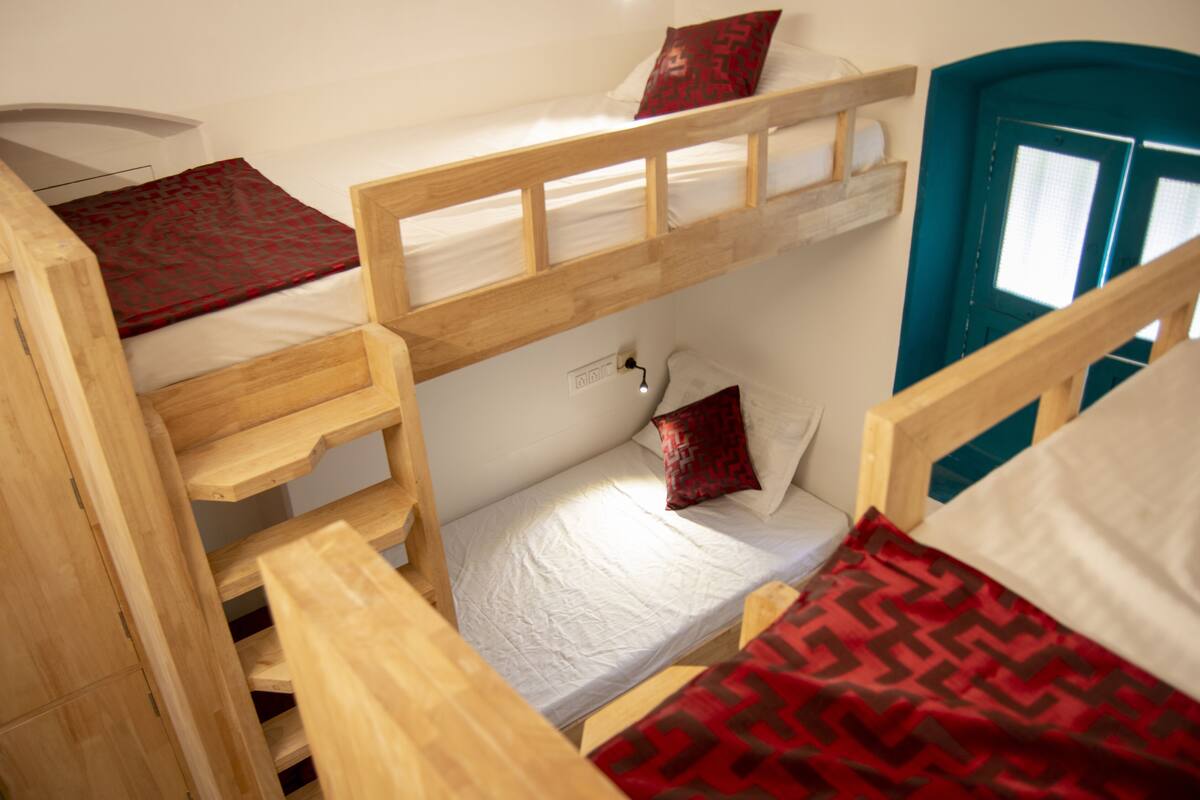 A bunk bed room with a wooden ladder, a door, and a window.