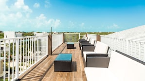 Eine Dachterrasse mit Gartenmöbeln und Blick auf die Stadt unter blauem Himmel.