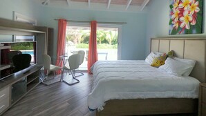 Ein Schlafzimmer mit einem Bett, einem Schreibtisch, einem Stuhl, einem Deckenventilator und einem Gemälde.
