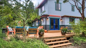 A two-story house with a deck, wooden benches, and outdoor seating. - Sehome Garden Inn (Bellingham)