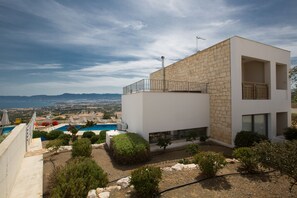 Une maison moderne à deux étages, dotée d’une piscine, d’une façade en pierre et offrant une vue sur le paysage.