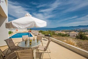 Une terrasse avec piscine, des sièges d’extérieur et une vue sur la côte.