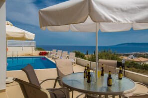 Un espace aménagé au bord de la piscine, avec une table, des chaises et des parasols.