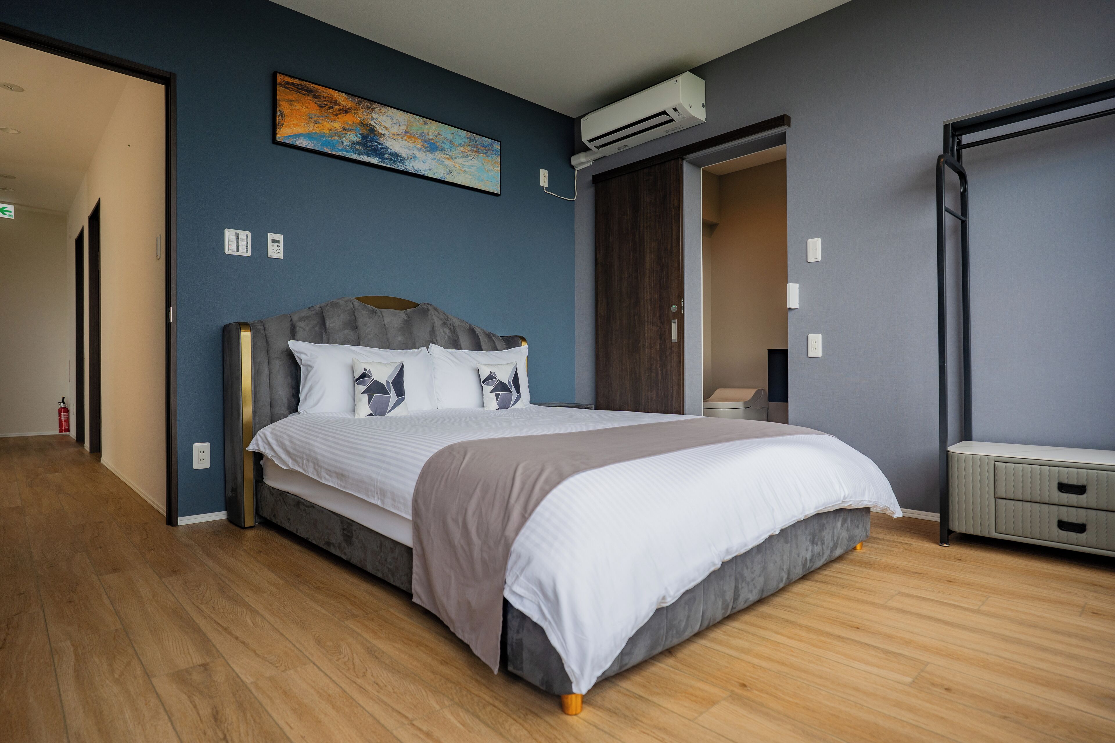 Un dormitorio moderno con una cama grande, un armario y un equipo de aire acondicionado.